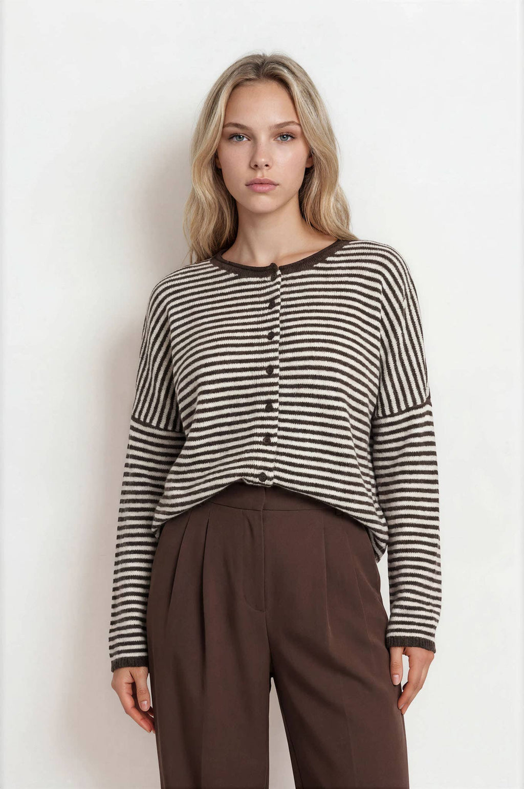 Woman wearing a striped shirt and brown pants against a white background