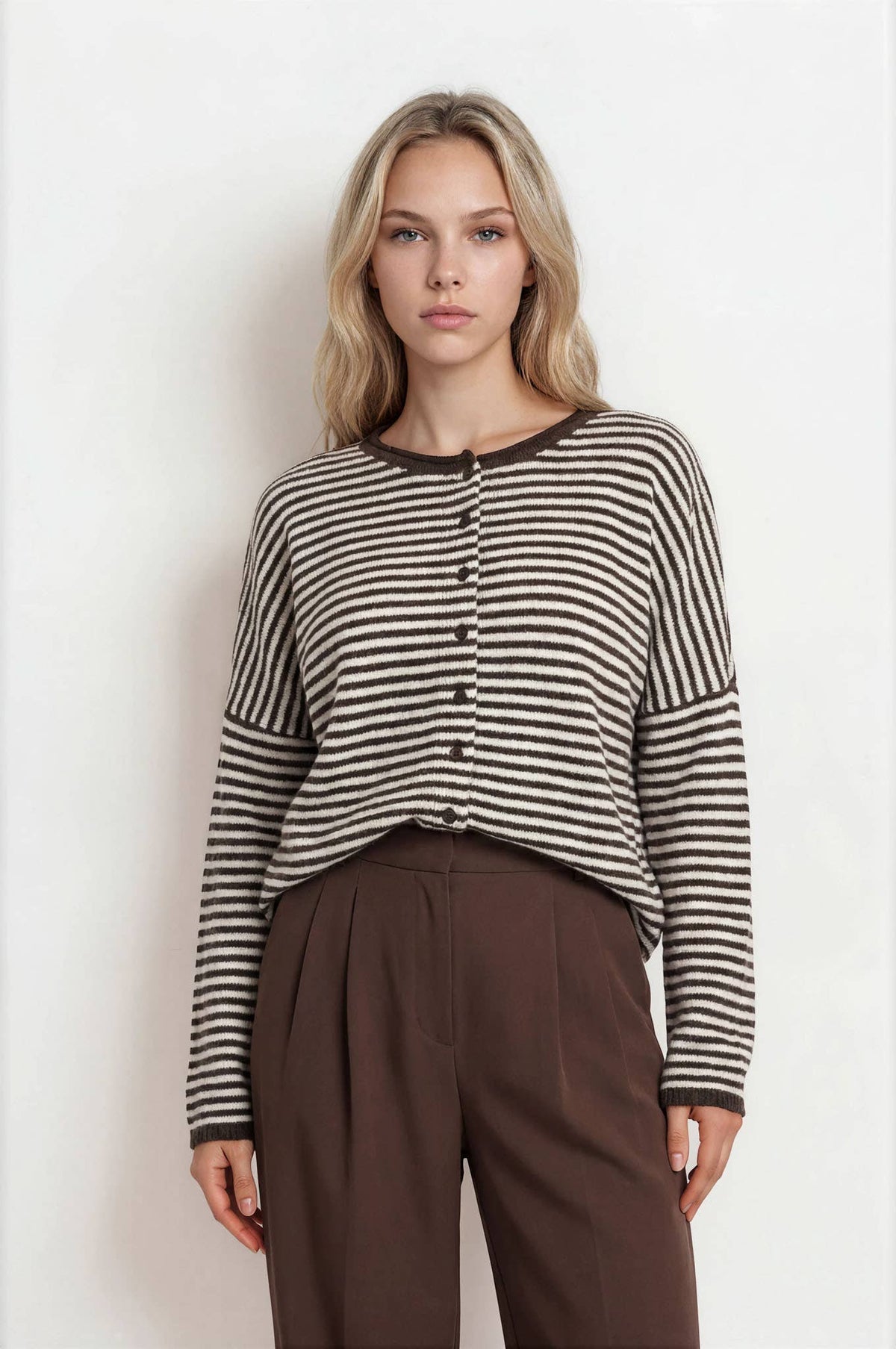 Woman wearing a striped shirt and brown pants against a white background